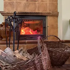 Płonący kominek z drewnem w wiklinowych koszach i ozdobnymi wazonami.