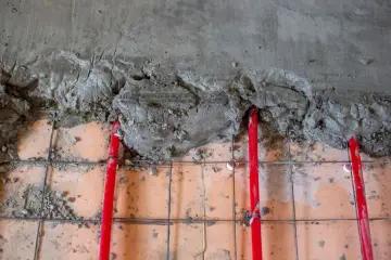 Czerwone rury ogrzewania podłogowego pod mokrą wylewką betonową.